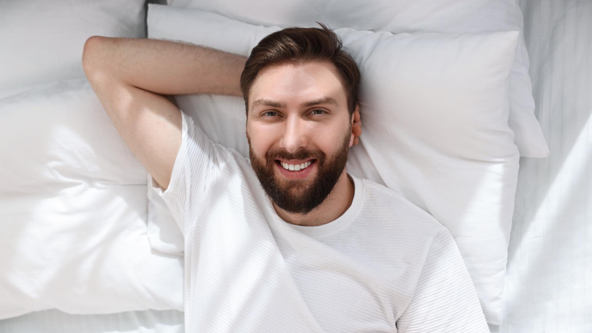 man laying in bed looking happy