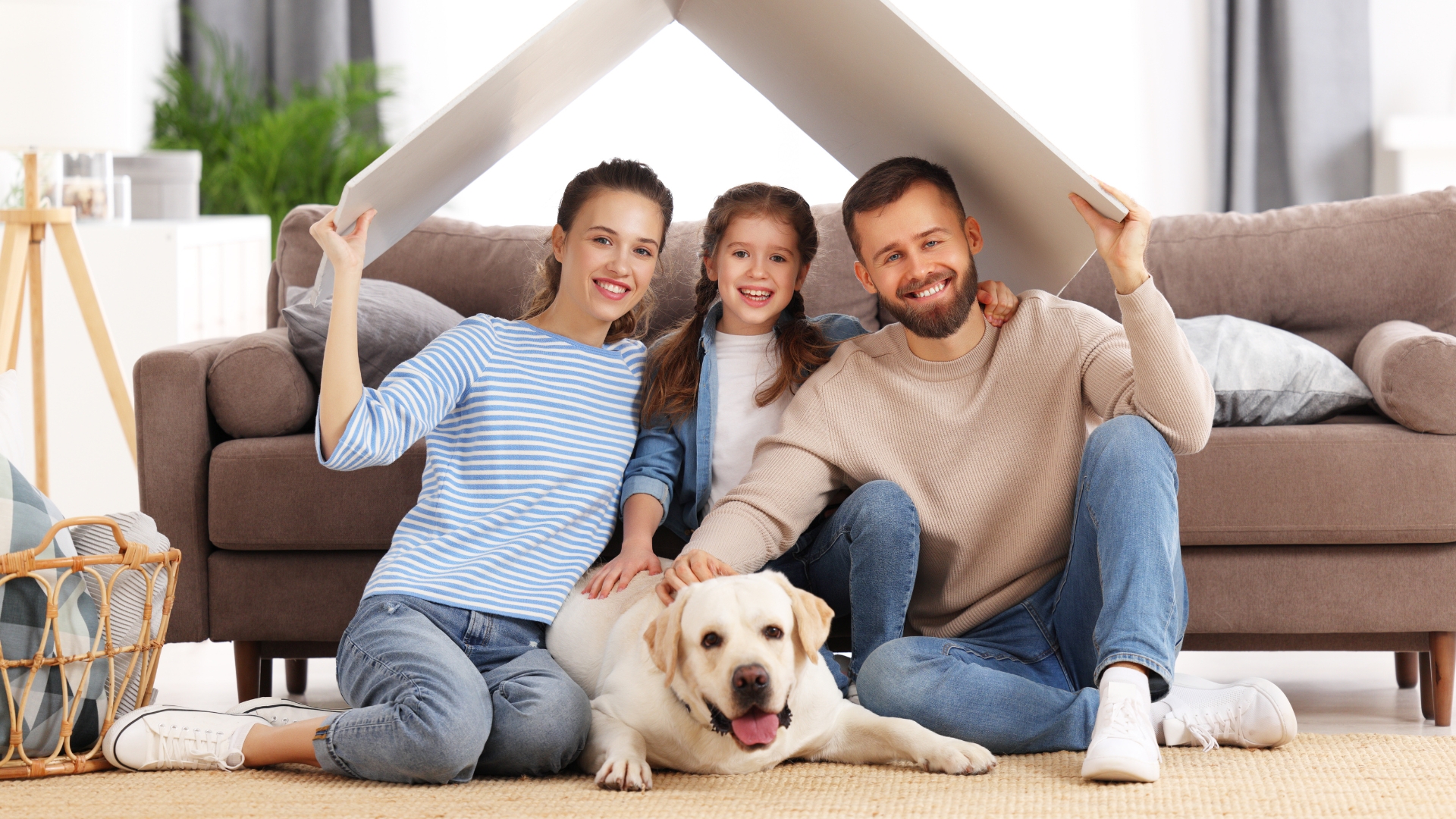 A happy Australian family sitting with their dog under a symbolic roof cutout, representing household health protection and human parasite medication options